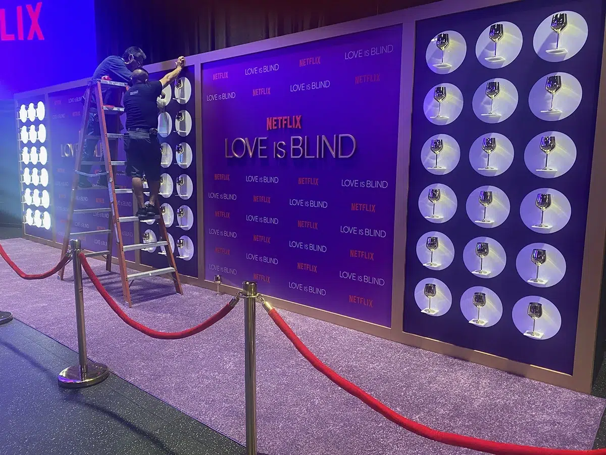 Branded backdrop with wine glass displays and red carpet entrance at a brand activation event